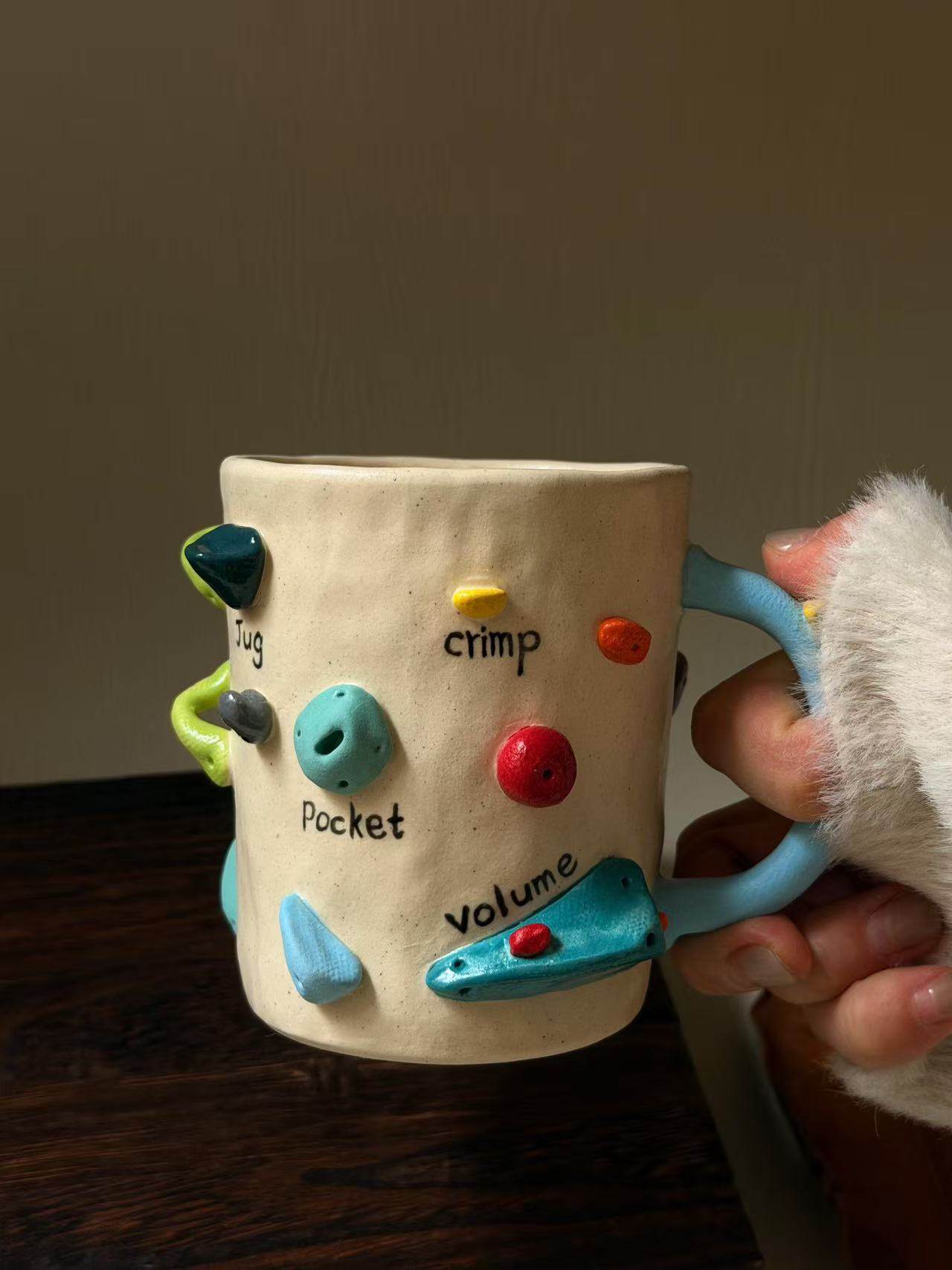 Handmade ceramic mug with rock climbing design, suitable for coffee, milk, and both hot and cold drinks.